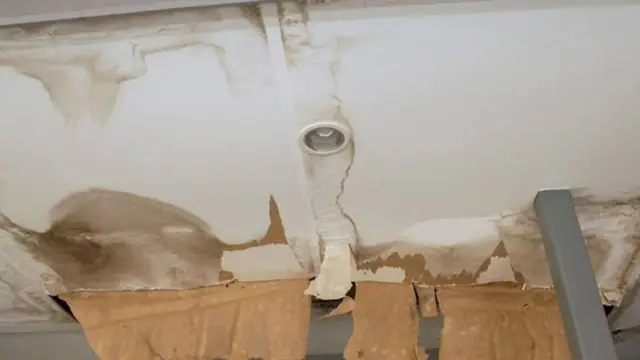 Water-stained ceiling with a pipe and peeling paint