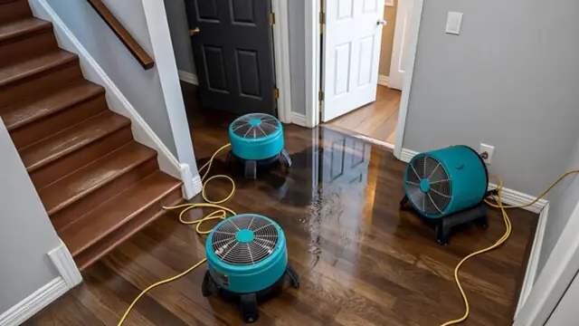 Air movers drying a hardwood floor near a staircase
