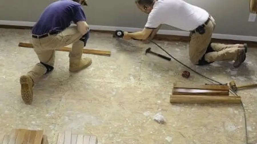 Two technicians kneeling to inspect a wet floor
